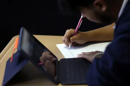 Audible Miranda Cambron takes notes as he prepares for the digital SAT, Wednesday, March 6, 2024, at Holy Family Cristo Rey Catholic High School in Birmingham, Ala. (AP Photo/Butch Dill)