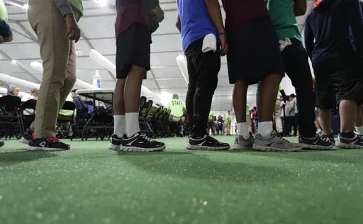 In this July 9, 2019, file photo, immigrants line up in the dinning hall at the U.S. government's newest holding center for migrant children in Carrizo Springs, Texas. The Biden administration plans to partially end the 27-year-old court supervision of how the federal government cares for child migrants, shortly after producing its own list of safeguards against mistreatment. (AP Photo/Eric Gay, File)