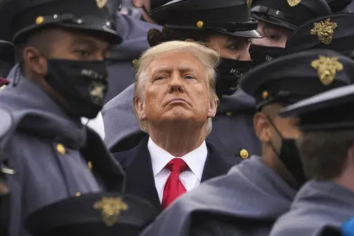Surrounded by Army cadets, President Donald Trump watches the first half of the 121st Army-Navy Football Game in Michie Stadium at the United States Military Academy, Saturday, Dec. 12, 2020, in West Point, N.Y. Experts in constitutional law and the military say the Insurrection Act gives presidents tremendous power with few restraints. Recent statements by former President Donald Trump raise questions about how he might use it if he wins another term. (AP Photo/Andrew Harnik, File)