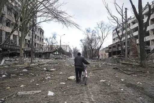 A man walks with a bicycle in a street damaged by shelling in Mariupol, Ukraine, March 10, 2022. In talks between Russia and Ukraine toward a possible cease-fire after three weeks of intense fighting, negotiators are exploring prospects of possible “neutrality” for Ukraine. (AP Photo/Evgeniy Maloletka, File)