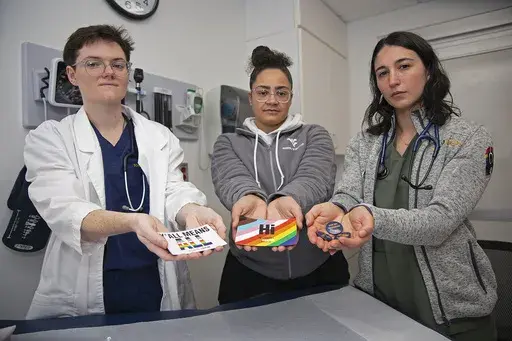 West Virginia University students El Didden, Bri Caison and Lia Farrell hold materials from the Rainbow Coats on Wednesday, March 8, 2023, in Morgantown, W.Va. (AP Photo/Kathleen Batten)