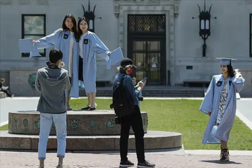 Columbia University class of 2020 graduates pose for photographs on Commencement Day on Wednesday, May 20, 2020, in New York. After three years, the pandemic-era freeze on student loan payments will end in late August. It might seem tempting to just keep not making payments, but the consequences can be severe, including a hit to your credit score and exclusion from future aid and benefits. (AP Photo/Frank Franklin II, File)