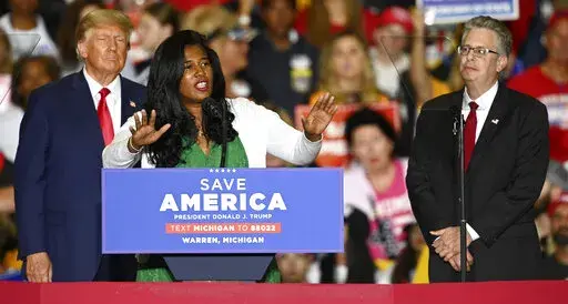 Former President Donald Trump, left, and Michigan Republican attorney general candidate Matt DePerno, right, listen as Michigan Republican secretary of state candidate Kristina Karamo addresses the crowd during a rally at the Macomb Community College Sports & Expo Center in Warren, Mich., Saturday, Oct. 1, 2022. Karamo, a community college instructor, ran as a far-right candidate in the 2022 midterms after becoming one of the most prominent election conspiracists in the country. (Todd McInturf/D