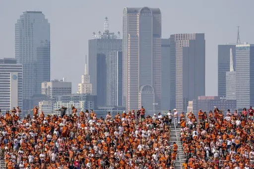The Dallas skyline rises behind the Cotton Bowl stands as Texas fans watch during the first half of an NCAA college football game against Oklahoma at the Cotton Bowl, Saturday, Oct. 8, 2022, in Dallas. U.S. metropolitan areas increased their populations by almost half a percent last year in another sign that flight from urban areas during the first year of the pandemic either slowed down or reversed in its second year as people moved to Sunbelt metros in Texas and Florida by the tens of thousand