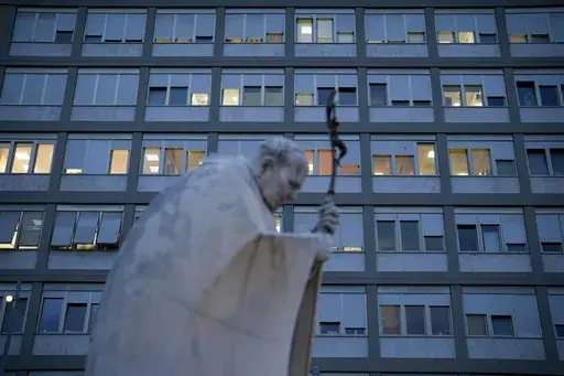 A marble statue of late Pope John Paul II is backdropped by the Agostino Gemelli Polyclinic in Rome, Saturday, Feb. 15, 2025, where Pope Francis was hospitalized Friday after a weeklong bout of bronchitis worsened and is receiving drug therapy for a respiratory tract infection. (AP Photo/Gregorio Borgia)