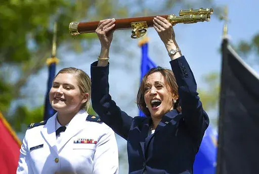 Vice President Kamala Harris lifts the school scepter at the conclusion of the U.S. Coast Guard Academy's 141st Commencement Exercises Wednesday, May 18, 2022 in New London, Conn. At left is Carolyn Ziegler, the last cadet of the 250 to graduate.  (AP Photo/Stephen Dunn)