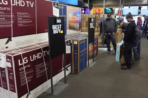 Customers debate on a television selection, Friday, Nov. 26, 2021, in Indianapolis.  Large retailers like Target, Macy’s and Ikea now offer “buy now, pay later” when customers check out. This payment method is spreading to local businesses, too.   (AP Photo/Darron Cummings, File)