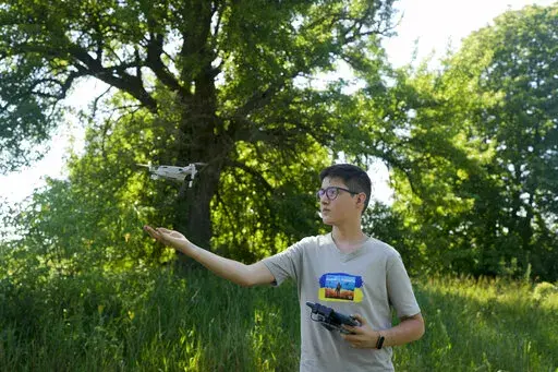 Andriy Pokrasa, 15, lands his drone on his hand during an interview with The Associated Press in Kyiv, Ukraine, Saturday, June 11, 2022. Andriy is being hailed in Ukraine for stealthy aerial reconnaissance work he has done with his dad in the ongoing war with Russia. They used their drone to help the country's military spot, locate and destroy Russian targets in the early days of the Russian invasion. (AP Photo/Natacha Pisarenko)
