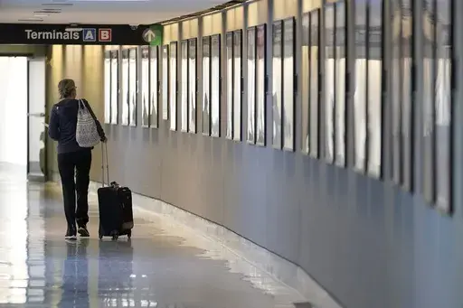 A traveler pulls their luggage between terminals at Logan International Airport, Wednesday, Jan. 11, 2023, in Boston. Travel experts say they aren’t seeing any dip in travel demand for the busy summer season or shoulder seasons, but people will likely spend a lot more money this year to take their vacation. Prices for flights, car rentals and hotels are still 15% higher than before the pandemic, though they have come down a bit from last year. (AP Photo/Steven Senne, File)