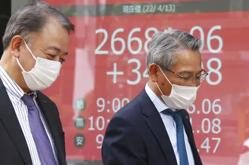 People walk by an electronic stock board of a securities firm in Tokyo, Wednesday, April 13, 2022. Asian shares were mostly higher Wednesday on hopes that the curbs on U.S. interest rates may moderate after new data showed signs of slowing inflation. Benchmarks rose in early trading in Japan, South Korea and Australia, while slipping in China. (AP Photo/Koji Sasahara)