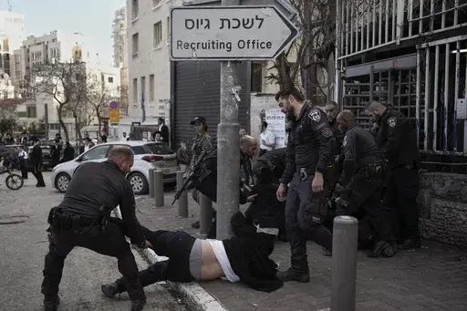 Israeli police officers scuffle with ultra-Orthodox Jewish men during a protest against possible changes to the military draft laws, outside a military recruitment office in Jerusalem, on March 4, 2024. Israel's High Court ruling Thursday to curtail subsidies for ultra-Orthodox men has thrown Prime Minister Benjamin Netanyahu's political future into grave jeopardy. Netanyahu now has until Monday to present the court with a plan to dismantle what the justices called a system that privileges the u