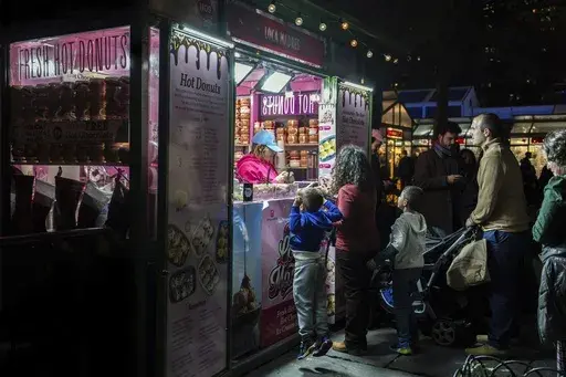 People wait in line for hot donuts at Bryant Park's Winter Village, Tuesday, Nov. 26, 2024, New York. (AP Photo/Julia Demaree Nikhinson, File)