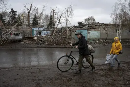 Locals walk past a house which was destroyed by Russian attack in Kostiantynivka, Ukraine, Thursday, April 6, 2023. (AP Photo/Evgeniy Maloletka)