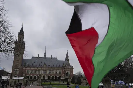 A Palestinian flag flies outside the United Nations' highest court, rear, during historic hearings in The Hague, Netherlands, Wednesday, Feb. 21, 2024, into the legality of Israel's 57-year occupation of the West Bank and east Jerusalem, plunging the 15 international judges back into the heart of the decades-long Israeli-Palestinian conflict. Six days of hearings at the International Court of Justice, during which an unprecedented number of countries will participate in proceedings, are schedule