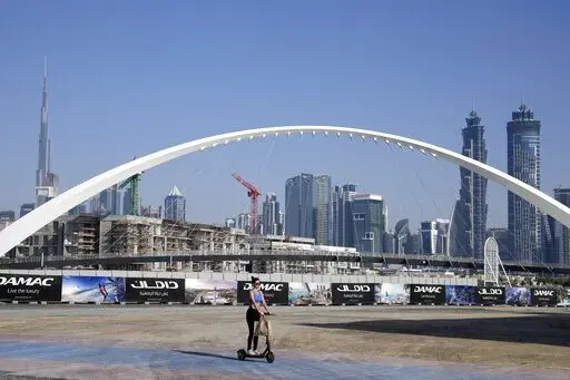 A woman rides a scooter while passing by the advertising billboards of a new residential project in Dubai, United Arab Emirates, Tuesday, Jan. 31, 2023. For the first time since a 2009 financial crisis nearly brought Dubai to its knees, several major abandoned real estate projects now show signs of life. As with its other booms, war again is driving money into Dubai and buoying its economy. This time it's Russian investors fleeing Moscow’s war on Ukraine, rather than people escaping Mideast ba