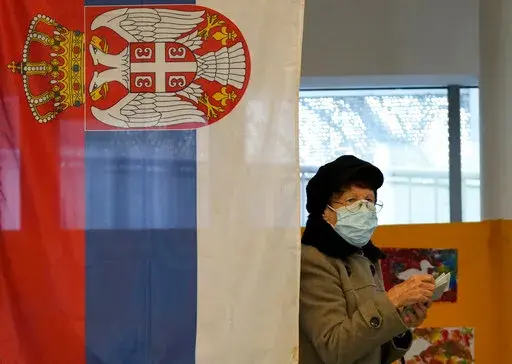 A woman wearing a face mask to protect against coronavirus, prepares to vote at a polling station in Belgrade, Serbia, Sunday, April 3, 2022. Voters in Serbia cast ballots Sunday in a triple election likely to keep in power a populist government in the Balkan country that has refused to impose sanctions on Russia over the war in Ukraine. (AP Photo/Darko Vojinovic)