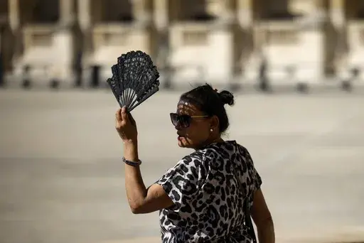 A woman uses a fan in the courtyard of the Louvre museum, Sept. 7, 2023, in Paris. After a summer of record-smashing heat, warming somehow got even worse in September as Earth set a new mark for how far above normal temperatures were, the European climate agency reported Thursday, Oct. 5. (AP Photo/Thomas Padilla, File)