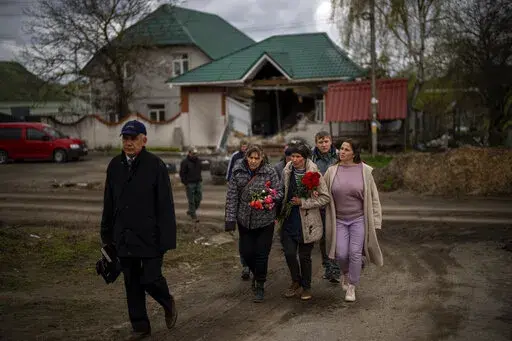 Tetiana Boikiv, 52, center, walks with friends and neighbors during a funeral service for her husband, Mykola "Kolia" Moroz, 47, in the Ukrainian village of Ozera, near Bucha, on Tuesday, April 26, 2022. Russian soldiers took Kolia from his house on March 15. He was tortured and shot, his body found two weeks later in a village 15 kilometers (9 miles) away where Russians set up a major forward operating base for their assault on the capitol, Kyiv. (AP Photo/Emilio Morenatti)