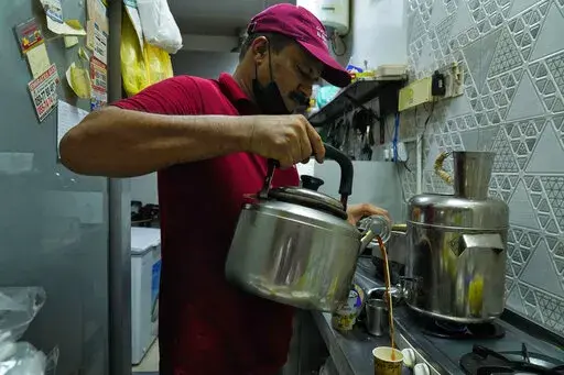 An Indian tea seller who gave his name as Rafik pours karak in Dubai, United Arab Emirates, Wednesday, Aug. 24, 2022. Karak is the informal national drink of the United Arab Emirates, long priced at just 1 dirham, a bit less than 30 U.S. cents. But now, as supply chain shortages and Russia's war on Ukraine lead to price spikes across the world, Dubai's tea sellers are bumping up prices to 1.50 dirhams, or just over 40 cents. That's a blow to migrant workers who depend on the drink as a daily rit