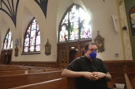 The Rev. Manuel Rodriguez sits in the pews of his church, Our Lady of Sorrows, on March 5, 2021, in the Queens borough of New York. A new survey by the Pew Research Center, Tuesday, March 28, 2023, says in-person attendance at religious services in the U.S. declined during the COVID-19 pandemic. But Rodriguez says attendance is now higher at his Catholic church than before the pandemic, even though more than 100 of his parishioners died of COVID. (AP Photo/Jessie Wardarski, File)