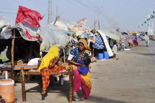 Displaced families who fled their flood-hit homes take refuge along a roadside in Jamshoro, southern Sindh province, Pakistan, Friday, Sept. 16, 2022. The devastating floods affected over 33 million people and displaced over half a million people who are still living in tents and make-shift homes. The water has destroyed 70% of wheat, cotton and other crops in Pakistan. (AP Photo/Pervez Masih)