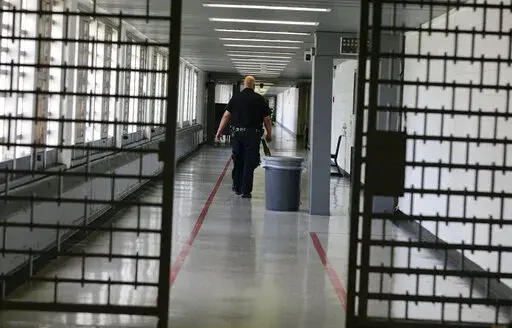 A Rikers Island juvenile detention facility officer walks down a hallway of the jail, Thursday, July 31, 2014, in New York. It's hard to find anyone on board with New York Gov. Kathy Hochul's plan to toughen the state's bail laws, two years after they were retooled to keep people from being jailed because they are poor. The debate over bail in New York has been fierce enough to delay passage of the state's budget. (AP Photo/Julie Jacobson, File)