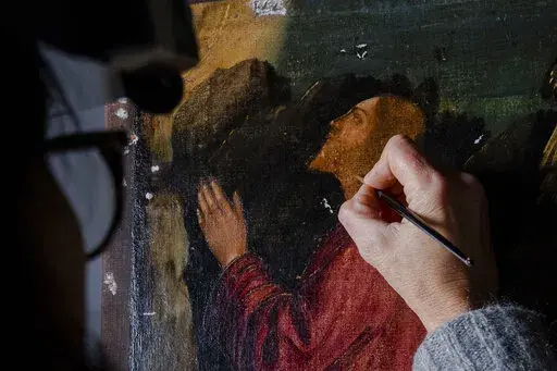 Restorer Valentina Piovan works on Vittore Carpaccio's 1502 painting 'The agony in the garden' at the Dalmatian School in Venice, northern Italy, Wednesday, Dec. 7, 2022. On November 20th, the National Gallery of Washington inaugurated the first retrospective exhibition of Carpaccio’s works outside of Italy. It will run until February 12, 2023. (AP Photo/Domenico Stinellis)