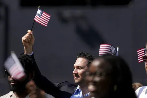 A man, part of a group of 50 new United States citizens from 25 different countries, takes part in a naturalization ceremony before the San Diego Padres host the Minnesota Twins in a baseball game at Petco Park, Wednesday, Aug. 21, 2024, in San Diego. (AP Photo/Gregory Bull)
