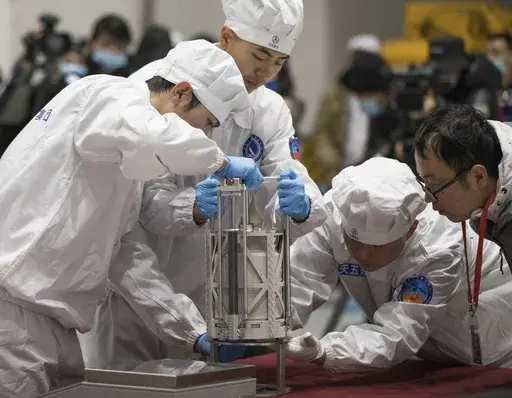 In this Thursday, Dec. 17, 2020 photo provided by China's Xinhua News Agency, technicians prepare to weigh a container carrying moon samples retrieved by China's Chang'e 5 lunar lander in Beijing. In a report published in the journal Nature Geoscience on Monday, March 27, 0223, scientists announced they have discovered a new and renewable source of water on the moon for future explorers in the lunar samples. Water was embedded in tiny glass beads in the lunar dirt where meteorite impacts occur. 