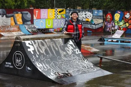 Sara Campos poses at tennis courts being converted to a skatepark at Portland State University in Portland, Ore., Friday, Oct. 28, 2022. Campos is a fellow in Tony Hawk's The Skatepark Project program, which is training 15 skateboarding enthusiasts in community organizing and project management so they can build a skatepark in their neighborhoods. (AP Photo/Steve Dipaola)