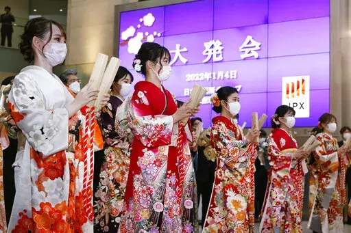 Workers attend a ceremony to mark the first trading day of the year at Osaka Exchange in Osaka, western Japan Tuesday, Jan. 4, 2022. The Japanese sign reads "The first trading day." (Kyodo News via AP)
