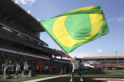 An Oregon cheerleader waves a flag following an Oregon touchdown against Oregon State during the second half of an NCAA football game, Saturday, Sept. 14, 2024, in Corvallis, Ore. (AP Photo/Amanda Loman)