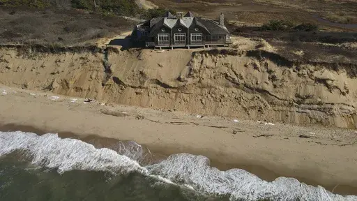 A home sits atop of a sandy bluff overlooking a beach in Wellfleet, Mass., Monday, Jan. 27, 2025. (AP Photo/Andre Muggiati)
