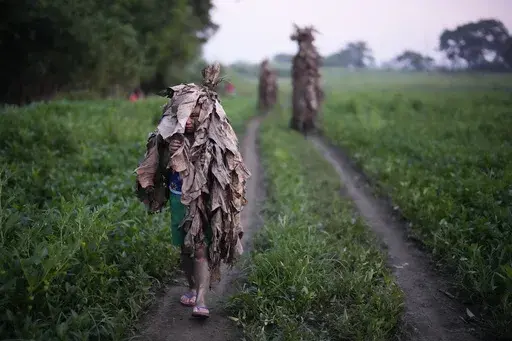 A Catholic boy walks towards the church of Saint John the Baptist during the “Taong Putik” or mud people festival at Bibiclat, Nueva Ecija province, northern Philippines, Monday, June 24, 2024. (AP Photo/Aaron Favila)
