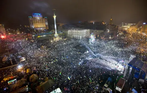 In this Jan. 1, 2014, file photo Pro-European Union activists hold lights as they sing the Ukrainian national anthem, celebrating the New Year in Kyiv's main square. At least 100,000 Ukrainians gathered in a sign of support for integration with Europe. On Nov. 21, 2023, Ukraine marks the 10th anniversary of the uprising that eventually led to the ouster of the country’s Moscow-friendly president. (AP Photo/Efrem Lukatsky, file)