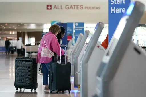 Travelers use the kiosk by the ticketing gate as they prepare for travel from Love Field airport, May 19, 2023, in Dallas. When booking flights, navigating extra fees and upgrades can be overwhelming, which is no accident. Behavioral economics, a field that combines psychology with traditional economics, highlights the many biases that drive us to pay more than we have to. (AP Photo/Tony Gutierrez, File)