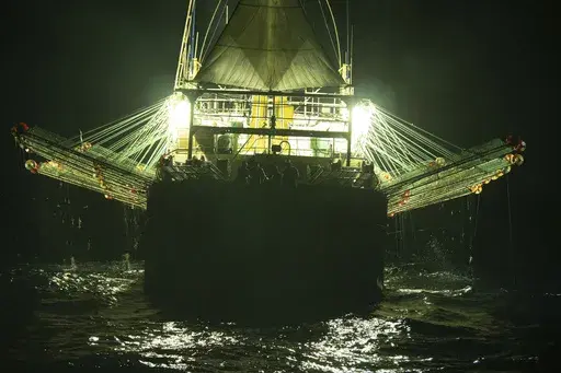 In this July 2021 photo provided by Sea Shepherd, the Chang Tai 802, a Chinese-flagged ship, fishes for squid at night on the high seas off the west coast of South America. Hazardous work conditions sometimes akin to slavery have been detected on nearly 500 industrial fishing vessels around the world, including this one, but identifying those responsible for abuses at sea is hampered by a lack of transparency and regulatory oversight, according to research by the Financial Transparency Coalition