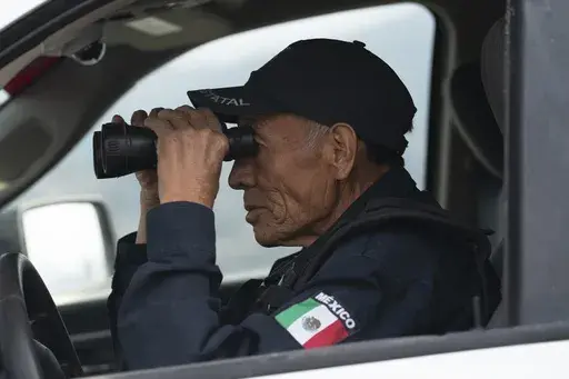 Nefi de Aquino, who works as a police officer and is also paid to keep an eye on the activity of the Popocatépetl volcano, looks at the volcano through his binoculars from Santiago Xalitzintla, Mexico, Thursday, 25 May 2023. De Aquino has been observing and reporting on the volcano´s activity since it started erupting again in 1994. (AP Photo/Marco Ugarte)