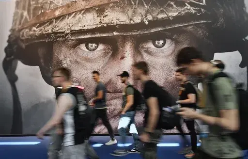 Visitors passing an advertisement for the video game 'Call of Duty' at the Gamescom fair for computer games in Cologne, Germany, on Aug. 22, 2017. The European Union on Monday approved Microsoft’s $69 billion purchase of video game maker Activision Blizzard, deciding the deal won’t stifle competition for popular console titles like Call of Duty and accepting the U.S. tech company’s remedies to boost competition in cloud gaming. (AP Photo/Martin Meissner, File)