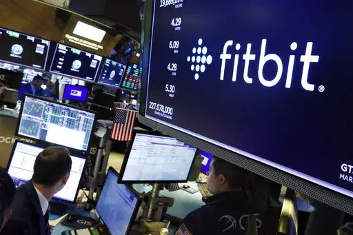 In this Oct. 28, 2019 file photo, the logo for fItbit appears above a trading post on the floor of the New York Stock Exchange.  Google-owned Fitbit has recalled 1 million of its Ionic smartwatches, Wednesday, March 2, 2022 after dozens of users reported burn injuries because the battery overheated. The fitness gadget maker says consumers who bought the $299 watches with the model number FB503 should immediately stop using the product and contact Fitbit for packaging to return them.  (AP Photo/R