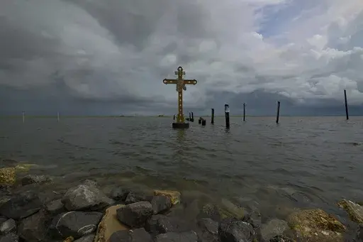 A cross erected on Shell Beach as a memorial to the residents in St. Bernard Parish, La. who died after Hurricane Katrina in 2005 is visible before Hurricane Ida makes landfall in New Orleans, Aug. 28, 2021. Hurricanes in the U.S. over last few decades killed thousands more people than meteorologists traditionally calculate and a disproportionate number of those victims are poor, vulnerable and minorities, according to a new epidemiological study released Wednesday, Aug. 16, 2023. (AP Photo/Matt