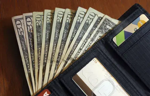In this June 15, 2018, file photo, cash is fanned out from a wallet in North Andover, Mass. The holidays are a time when travel, gift buying and family outings are abundant. The season can lead you to feel pressured to spend more than you usually would. For this reason, it’s important to have financial boundaries in place to safeguard your finances. The steps that can help you establish and uphold financial boundaries include creating a financial plan for 2024, learning how to say no, acknowle
