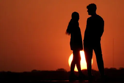 People are silhouetted against the sky as the sun sets Wednesday, May 11, 2022, in Kansas City, Mo. According to a report released by the U.S. Centers for Disease Control and Prevention on Thursday, April 27, 2023, the first years of the pandemic saw a huge decline in high school students having sex. Teen sex was already becoming less and less common before COVID-19. (AP Photo/Charlie Riedel, File)