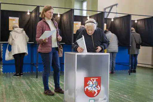An elderly woman casts her vote at the polling station during the first round of voting in parliamentary elections, in Vilnius, Lithuania, Sunday, Oct. 13, 2024. (AP Photo/Mindaugas Kulbis)