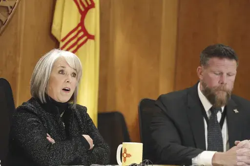 New Mexico Gov. Michelle Lujan Grisham, left, and Senior Public Safety Advisor Ben Baker, right, provide an update, Monday, Dec. 11, 2023, in Santa Fe, New Mexico, on a public health order aimed at reining in gun violence and drugs in the Albuquerque area that the governor describes as an epidemic. New Mexico could become an early political testing ground for a proposal to make assault-style weapons less deadly. (AP Photo/Morgan Lee)
