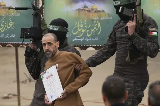 Israeli captive Eli Sharabi, who had been held hostage by Hamas in Gaza since Oct. 7, 2023, is escorted by Hamas fighters before being handed over to the Red Cross in Deir al-Balah, central Gaza Strip, Feb. 8, 2025. (AP Photo/Abdel Kareem Hana)