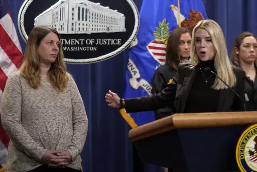 Attorney General Pam Bondi speaks at a news conference regarding immigration enforcement at the Justice Department, Wednesday, Feb. 12, 2025, in Washington, as Tammy Nobles, mother of Kayla Hamilton, listens. (AP Photo/Ben Curtis)