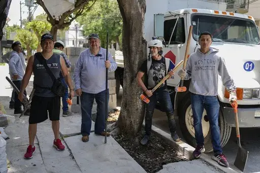 Arturo Hernandez, second from right, poses next to members of The Tree Army, a group that works to improve the urban forest, after breaking concrete placed on the roots of a tree in Mexico City, Monday, Aug. 26, 2024. (AP Photo/Eduardo Verdugo)