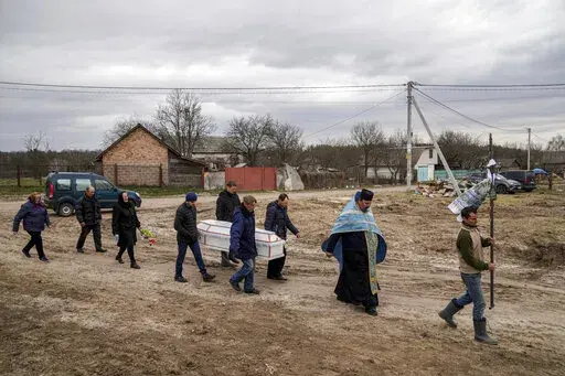 Liudmila Sumanchuk, third left, walks during the funeral ceremony for her granddaughter Veronika Kuts in Lgiv village, Chernihiv region, Ukraine, Friday April 8, 2022. Veronika Kuts who was 12-year-old was killed during a Russian airstrike. (AP Photo/Evgeniy Maloletka)