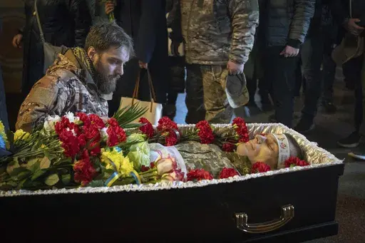A serviceman pays his last respects to late Ukrainian soldier Vasyl Ratushnyy, 28, during the funeral ceremony in St. Michael Cathedral in Kyiv, Ukraine, Wednesday, March 5, 2025. (AP Photo/Efrem Lukatsky)